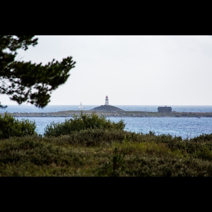 The view from our living room - Rauna: The island is a ridge of gravel and stone deposited by an Ice Age glacier, the mound a Bronze Age grave, the house a shelter for survivors of ship wrecks, and the light house to prevent the same.