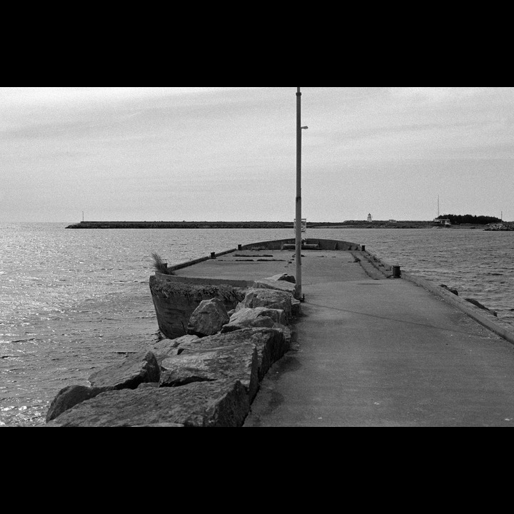 Tjørvehavn, Listahavn - the end of the pier in the shape of a ship is a grounded ferro-cemment hull. (B&W film)